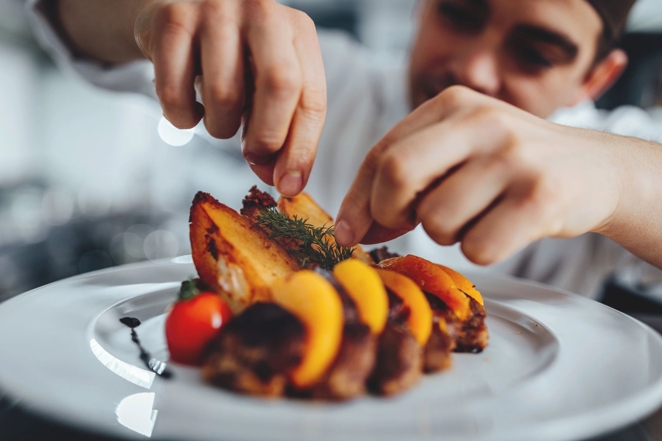 Cook carefully plating a dish in a kitchen