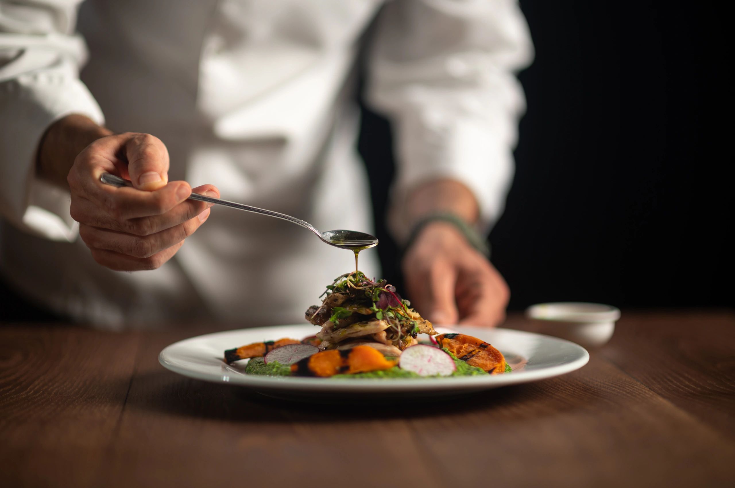 Chef pouring sauce onto a plated dish