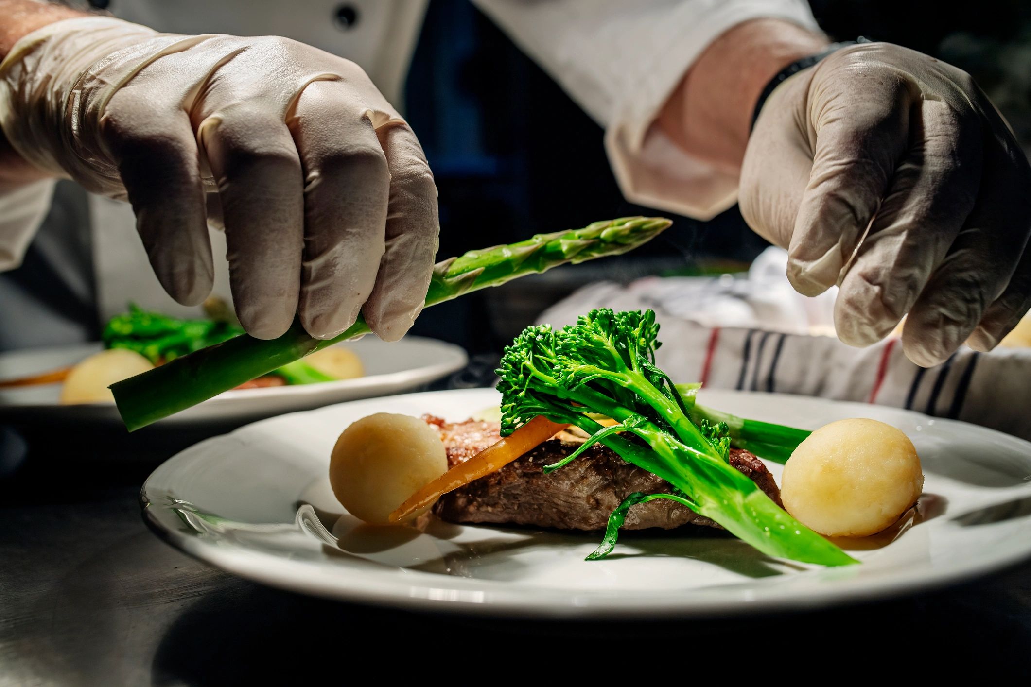Cook preparing a plated meal at a kitchen pass