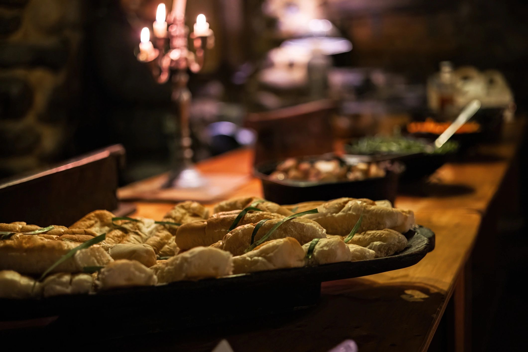 Buffet table with bread and assorted dishes in warm candlelight